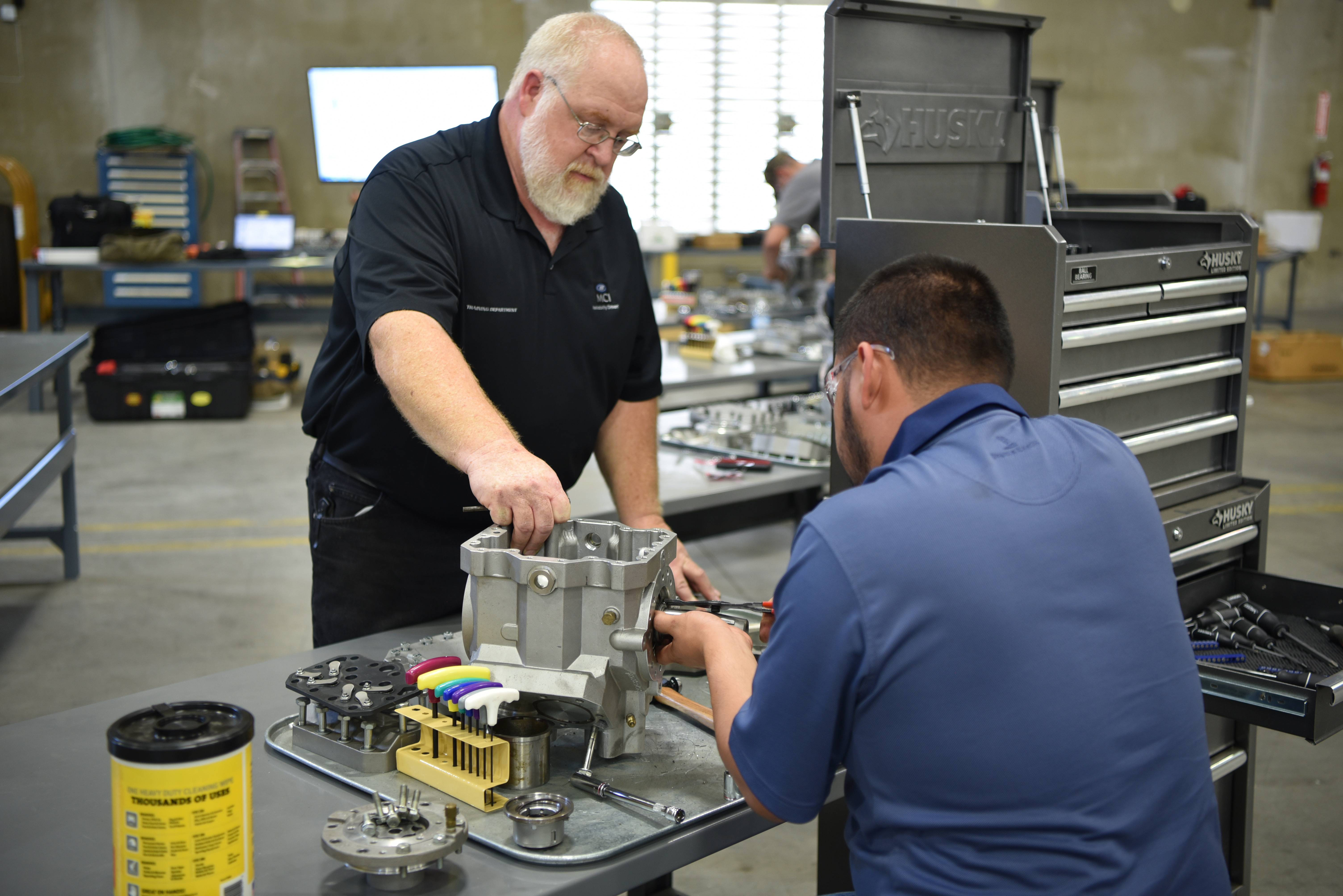 Workshop scene showing two men, one instructing the other on machine operation